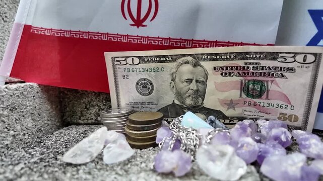 The Iranian flag, a fifty dollar bill, and coins are displayed on concrete.