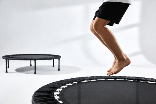 Energetic view of a child&rsquo;s legs in the air while jumping on a fitness mini trampoline in a bright, modern studio. A concept for active play on International Children's Day.