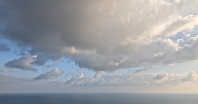 Clouds ocean sky with fluffy white and grey clouds drifting over a calm blue ocean horizon during the day