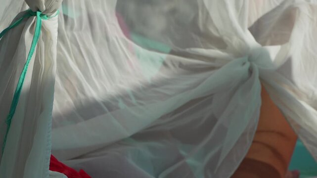 Fabric canopy poolside white sheer curtain blowing in the breeze over a sunbed creating a luxury vacation atmosphere on a bright day