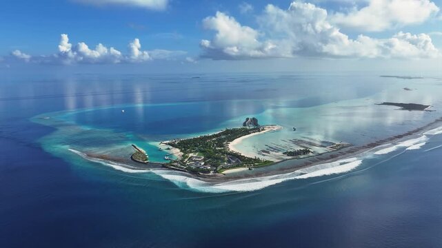 Aerial view of a resort featuring a turquoise lagoon, white sand beaches, and lush vegetation surrounded by deep blue ocean waters in Thulusdhoo, Kaafu Atoll, Maldives.