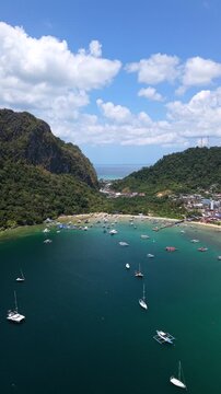 Aerial drone view of Corong Corong Bay in El Nido, Palawan, Philippines with turquoise water, tropical coastline, boats, and lush green islands under a sunny sky.