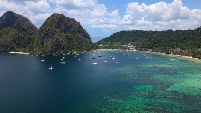 Aerial drone view of Corong Corong Bay in El Nido, Palawan, Philippines with turquoise water, tropical coastline, boats, and lush green islands under a sunny sky.