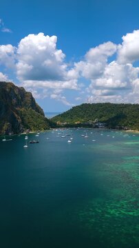 Timelapse aerial drone view of Corong Corong Bay in El Nido, Palawan, Philippines with turquoise sea, tropical mountains, anchored boats, and moving clouds above the coastline.