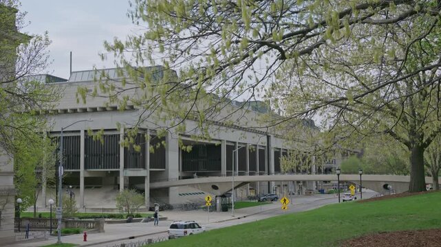 Cinematic gimbal dolly shot of University of Wisconsin campus road leading to walking bridge with smooth stabilized motion outdoors.