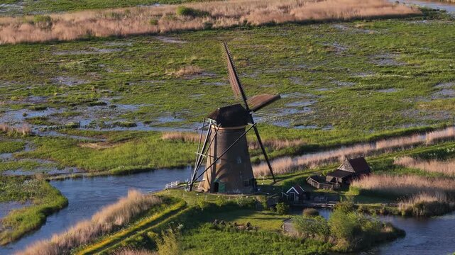 Dutch windmill spinning in scenic kinderdijk landscape at sunset