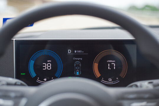 Active Regenerative Braking Telemetry. Dash panel monitors 38 mph velocity alongside battery charging algorithms. Bright azure rings contrast beautifully behind shadowed cabin focal points