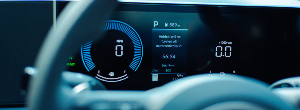 Parked Hybrid Telemetry Dashboard. Monitors parked status while displaying 589 mi range. Crisp amber numerals illuminate sleek glass screens behind shadowed modern cabin components
