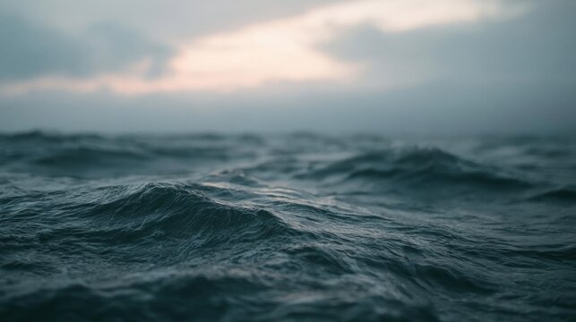 Close-up of the ocean waves. the water is dark and turbulent, with small waves crashing onto the shore. the sky is cloudy and the horizon is visible in the background.