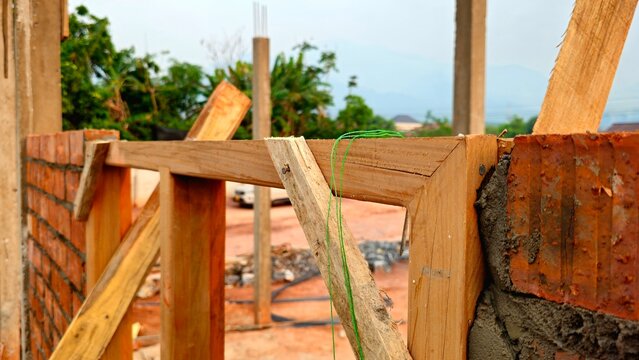 Brick Wall Construction with Wooden Formwork, Building Site in Progress. House Construction Site with Brickwork and Timber Frame Structure. traditional red clay bricks and wooden formwork.