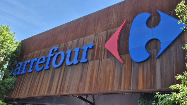 Large Carrefour storefront sign featuring blue typography and the red-and-blue logo on a weathered, rusted metal wall. Picture taken on May 7, 2026 in Bucharest, Romania.