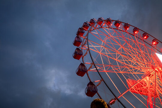 Illuminated Red Ferris Wheel Against a Dark Cloudy Night Sky