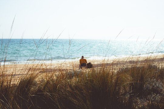 A man on a plastic chair admiring the sea
