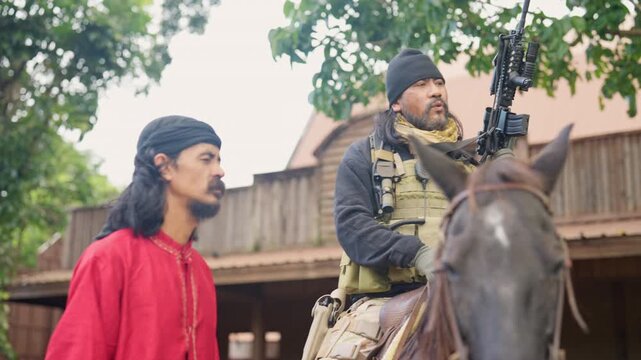 The combatant man who ride horse discuss with Arab man for fighting with the enemy in battle field and daylight.