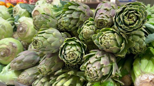 Raw green artichokes packed together in market display reveal rich leaf texture and natural organic freshness. Seasonal vegetable footage ideal for Mediterranean cuisine brands, cooking school. 