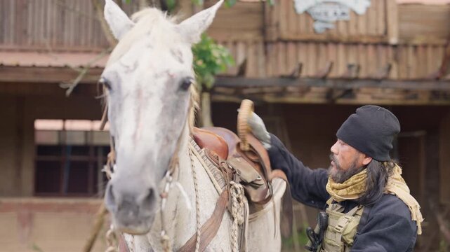 The combatant man prepare to ride horse by check rope that use to control riding horse then look around in daylight.