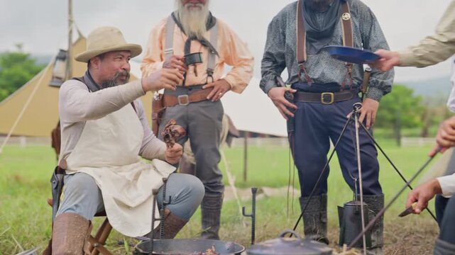 Close up view group of cowboy men with different generation enjoy with eating meal together in the field look like group of caravan.