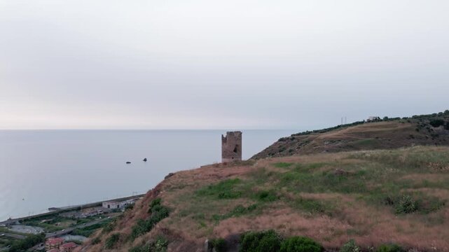 Drone on an ancient tower in Amantea, Italy. On a high hill on the seashore above the city. A cloudy summer day