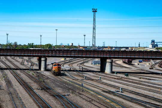 Minneapolis, Minnesota, USA - May 6, 2026 - A lone BNSF switching engine, number 684, passes beneath a train bridge in the Northtown Yard on a sunny spring day