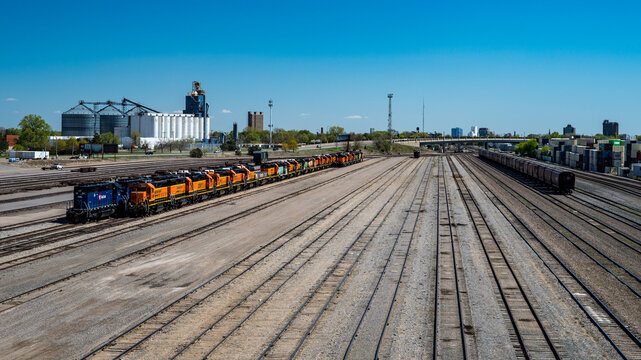 Minneapolis, Minnesota, USA - A line of retired BNSF and other locomotives, hopper cars, and shipping containers sit idle at Northtown yard on a sunny spring day