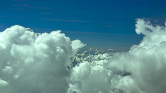 Immwersive pilot&rsquo;s eye view from a jet cockpit flying at 12000m high between the tops of threatening storm clouds, doing some turns to avoid turbulence.