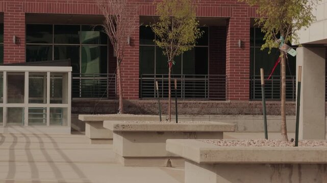 Smooth forward glide through urban courtyard with planters and young trees