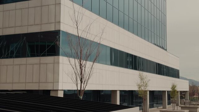 Smooth upward pan along glass office building with reflective windows and sky