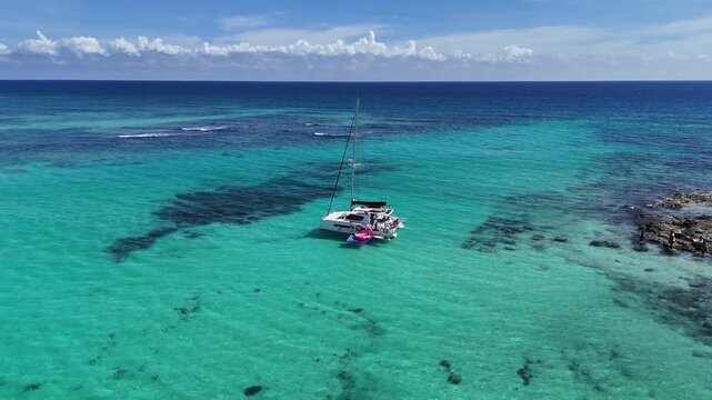 Aerial 360 drone shot of a modern sailboat on the turquoise Caribbean Sea at Xpuha Beach, Mexico, revealing the ocean, tropical beach, and lush Caribbean jungle. Perfect for travel