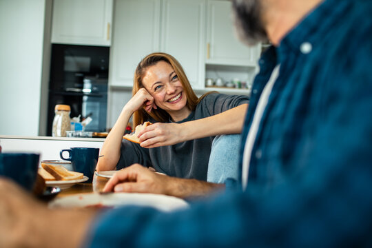 Smiling woman chatting with partner over breakfast at home kitchen
