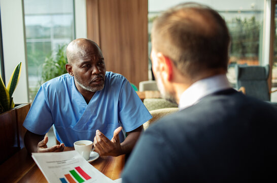 Healthcare worker and manager discussing reports in cafe