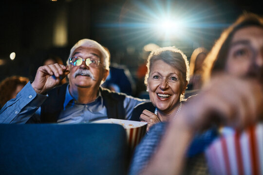 Happy senior couple watching a movie at the cinema