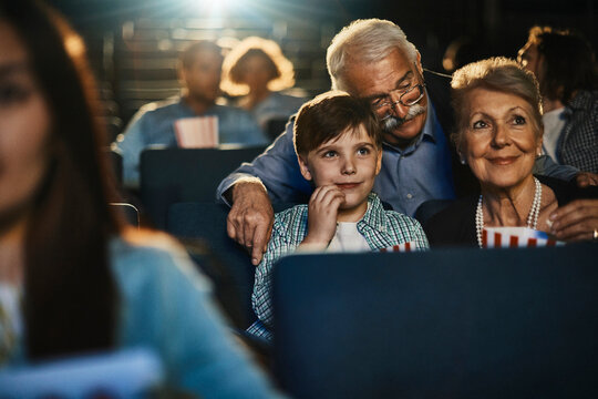 Grandparents and grandson watching movie in cinema