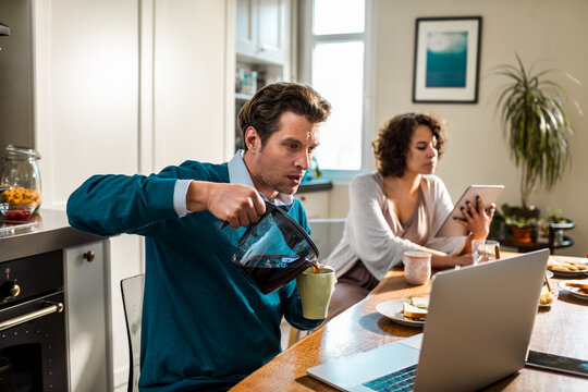 Couple working from home at kitchen table with coffee