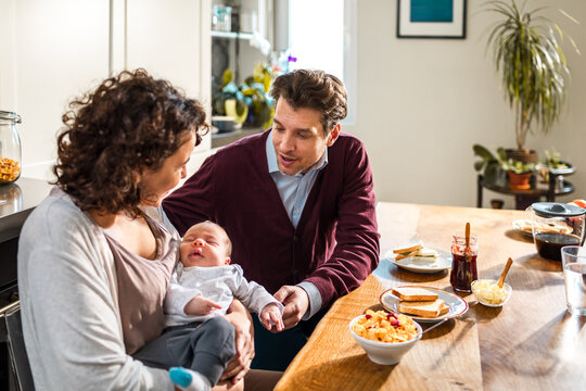 Parents with newborn during breakfast at home kitchen