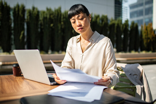 Professional woman reviewing paperwork at outdoor office terrace