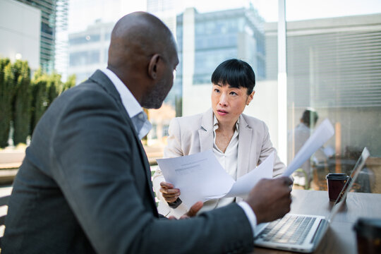 Colleagues discussing documents at outdoor office terrace