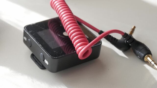 Compact lavalier mic and adapter set on a table in natural light