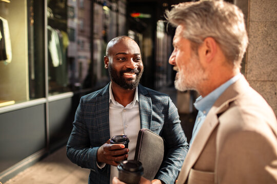 Business colleagues chatting with coffee on city street