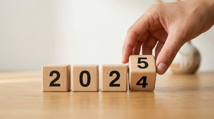 Naklejka premium A hand moving wooden blocks to change 2024 into 2025 representing new year investment and targets.