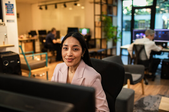 Smiling professional woman working at computer in modern coworking office