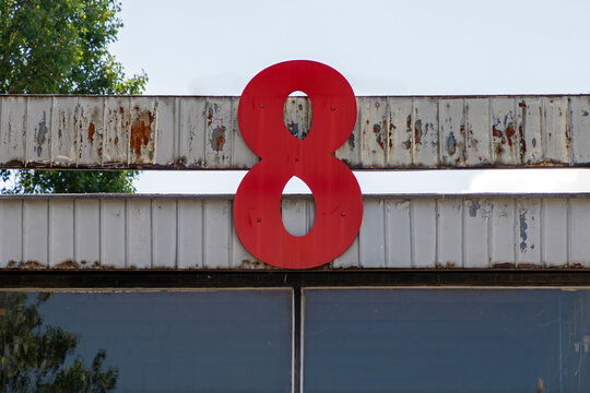 Metal number 8 sign on building fence outside on the road