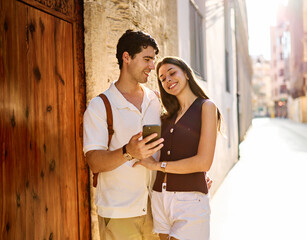 Naklejka premium Couple enjoys a sunny day walking together in a charming urban area during late afternoon or tourists visiting a destination looking at phone map app