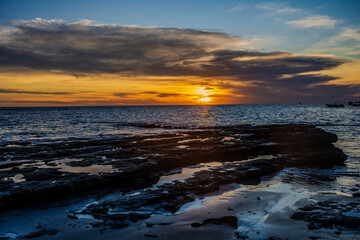 Obraz premium Sunset over the Indian Ocean with rocky coastline near Hell-Ville.