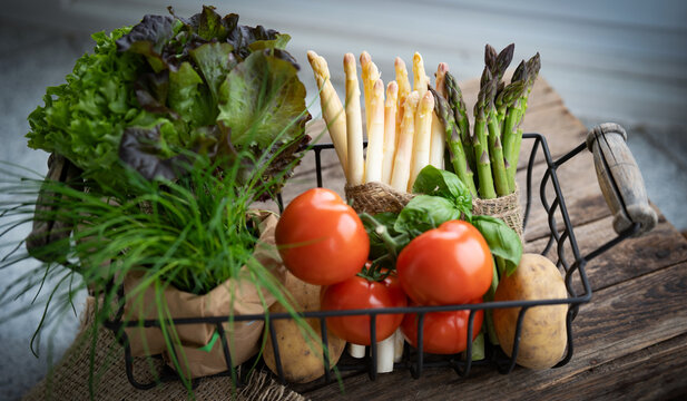 Basket with fresh colorful vegetables and salad on gray wood. Background for local shopping for healthy seasonal vegetables. 