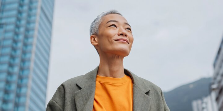 Young person smiling contemplative pose among tall buildings