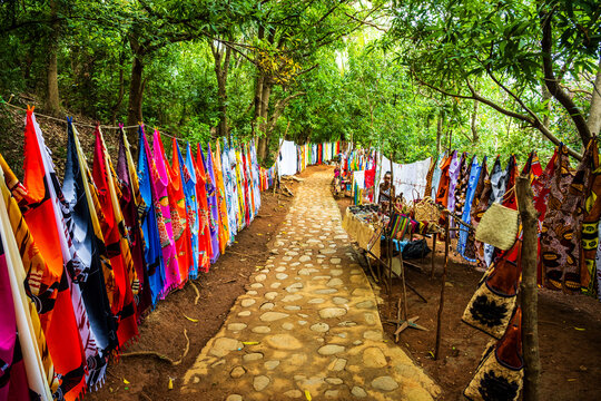 Colorful traditional fabrics lining a path on Nosy Komba between lush green trees