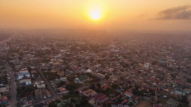 Hyperlapse Aerial view of Accra Ghana cityscape with orange golden sky at sunrise and sunset