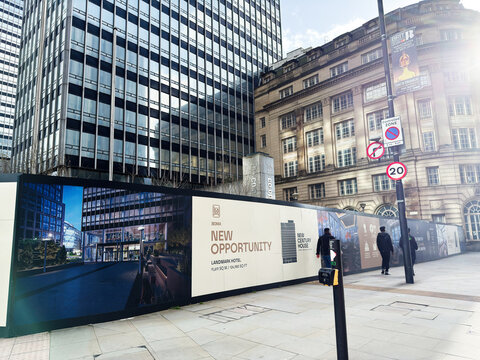 New opportunity construction hoarding outside modern Noma office buildings in Manchester, UK with pedestrians, signage and city development