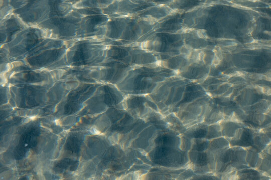 Peaceful clear ocean water ripple texture creating abstract sunlight reflection background pattern evoking calm relaxing feeling of nature in tropical marine environment