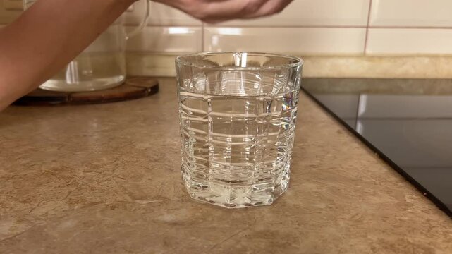 Effervescent vitamin C tablet falling into a transparent glass of water and dissolving with bubbles.